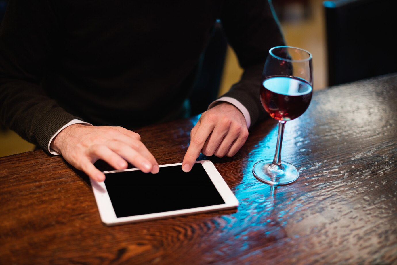 businessman-using-digital-tablet-with-wine-glass-counter_107420-65867